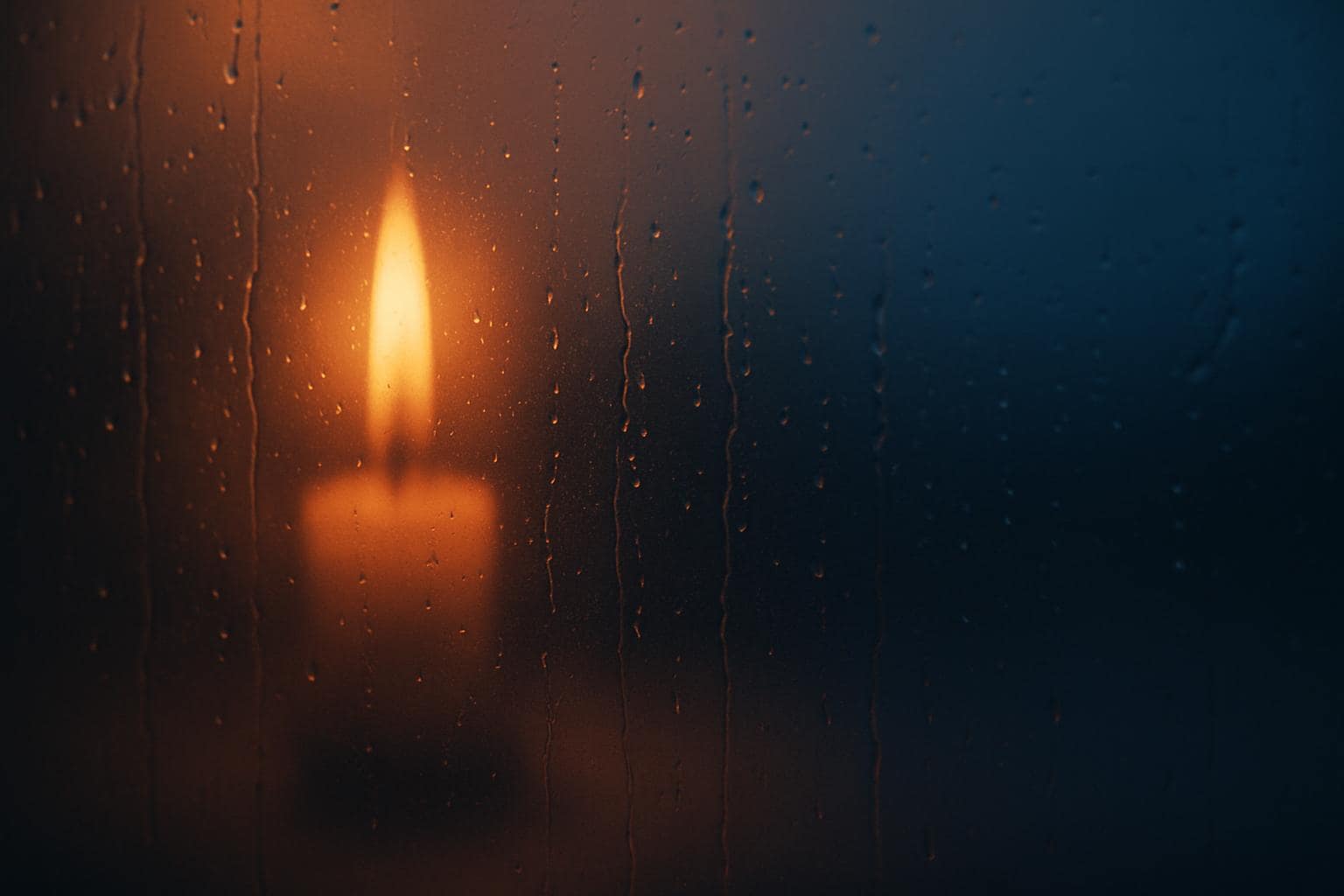 Candle flame reflected in a window at dusk, symbolizing new beginnings
